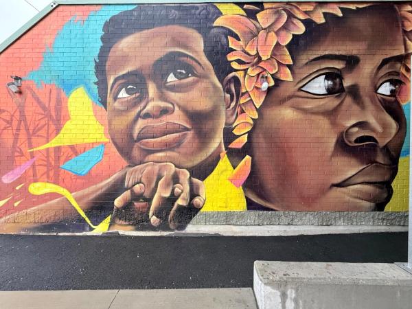 Mural in Chinatown with bright colors and two large faces painted by Kalkidan Assefa
