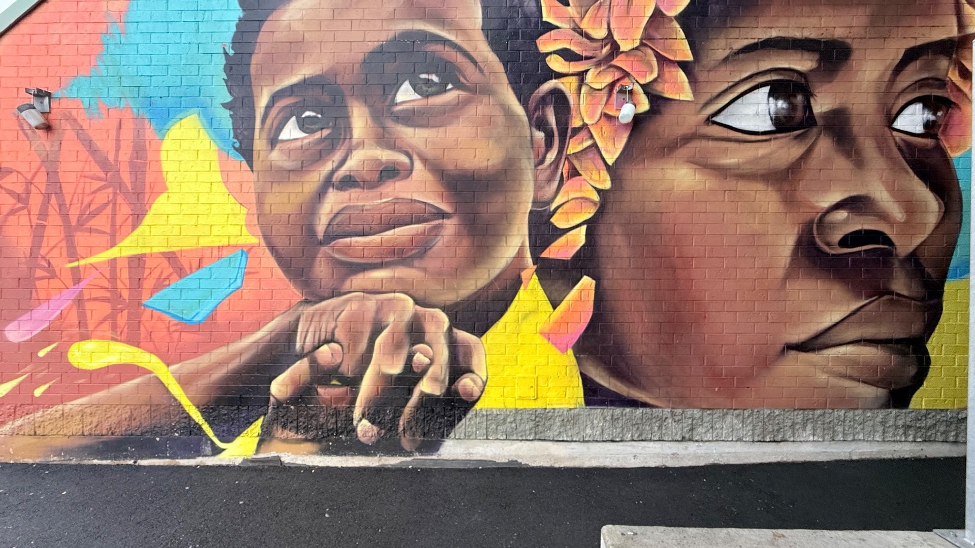 Mural in Chinatown with bright colors and two large faces painted by Kalkidan Assefa