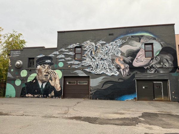 Phil Laporte's mural featuring realism, graffiti script, a shouting man, and two large faces. Ottawa's vibrant urban arts scene.