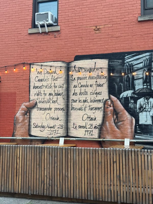 Artwork by Dan Metcalfe and Rob Lariviere (FallDown), showing a figure reading the ten demands for equal rights on a large Ottawa mural.