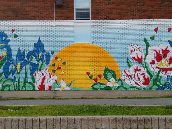 Vibrant Illunaata community mural by Maya Hum and OSA at Lowertown Community House. Celebrates Canadian diversity.