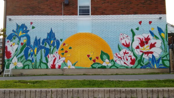 Vibrant Illunaata community mural by Maya Hum and OSA at Lowertown Community House. Celebrates Canadian diversity.