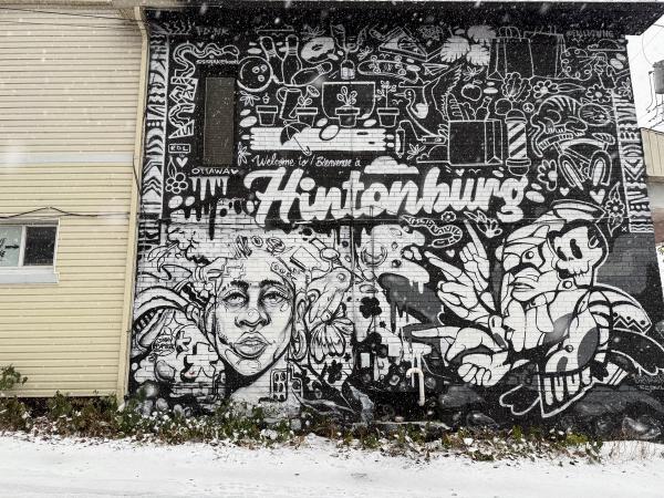 Jimmy Baptiste mural 'Welcome to Hintonburg' rendered in bold black and white graphic style on the brick wall of Urban Art Collective.