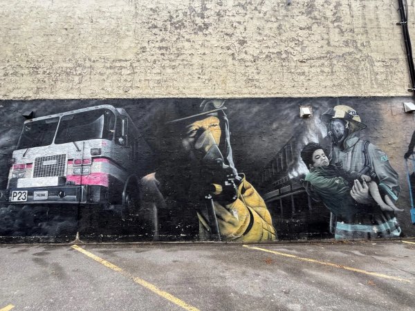 lack and white realism mural honoring Ottawa Firefighters, showing historical scenes, horses, steam engines, and a modern fire truck; located at 369 Richmond Road.