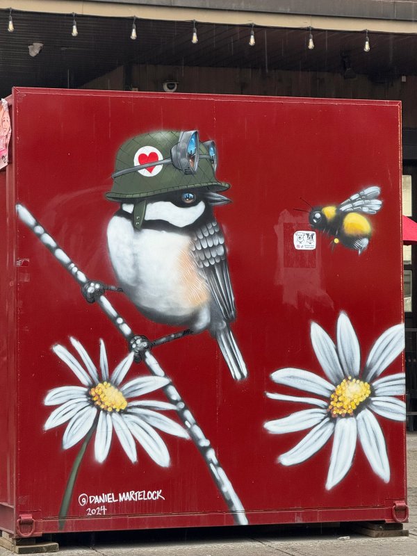 Street art in Byward Market, Ottawa: A detailed mural of a chickadee with aviator goggles on a red background by Daniel Martelock. OTTAWALLS documents this mural as a key piece of public art in the Ottawa-Gatineau urban art scene.