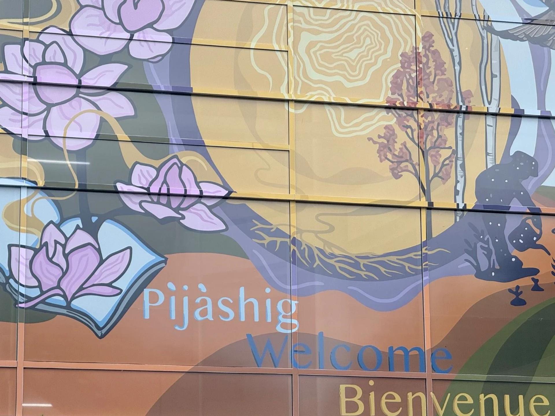 Colourful mural of pink lotus flowers, stylized trees, a dark figure, and "Pijàshig Welcome Bienvenue", Capital, Ottawa.