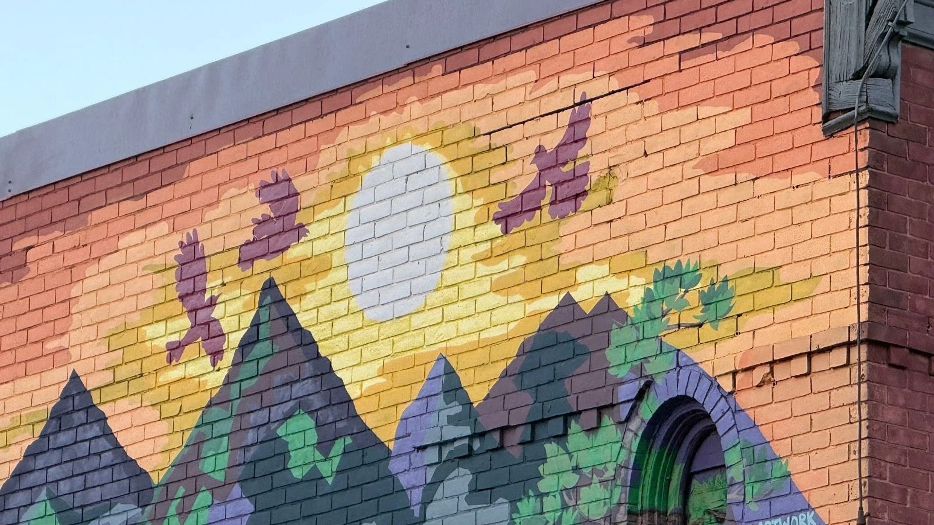 Artwork by Emilie Darlington in Chinatown, Ottawa featuring a bright sun and eagles