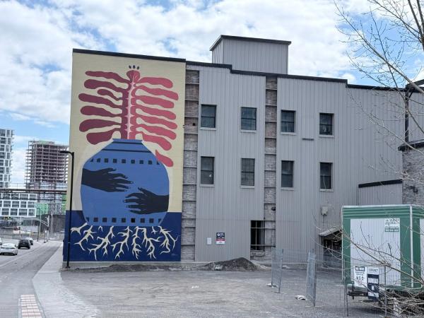 Huge 60ft mural titled We Are Seeds by Claudia Gutierrez and Kiana Meness on Eddy Street Gatineau, featuring a blue vase with red organic growth and white roots