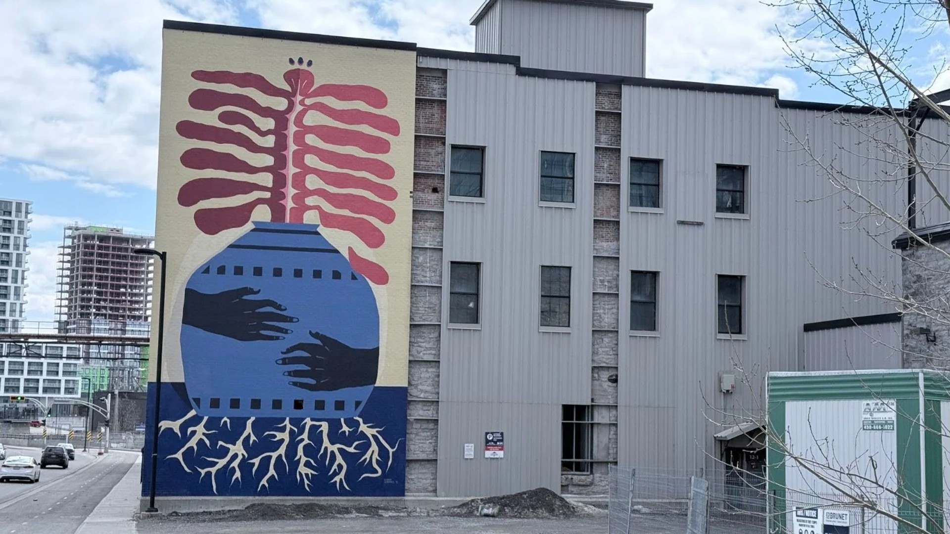 Huge 60ft mural titled We Are Seeds by Claudia Gutierrez and Kiana Meness on Eddy Street Gatineau, featuring a blue vase with red organic growth and white roots