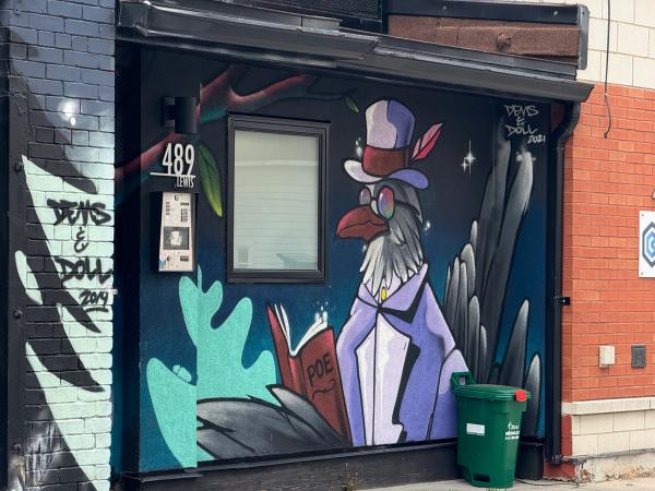 mural by Dems & Doll located in Centretown. The artwork depicts a stylized raven in a Victorian outfit and sunglasses holding a book.