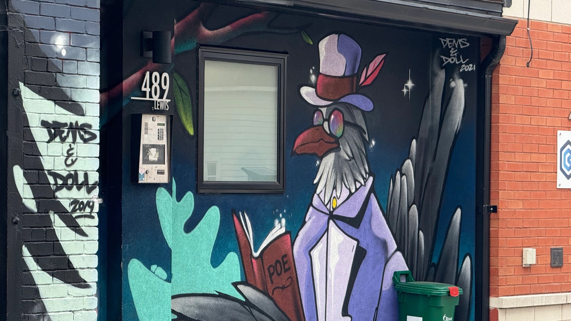 mural by Dems & Doll located in Centretown. The artwork depicts a stylized raven in a Victorian outfit and sunglasses holding a book.