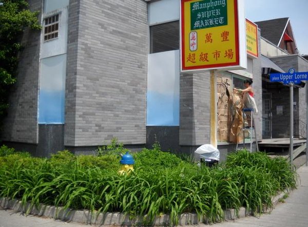 Photo of Maya Hum applying her sketch/masking on the side of the building in Chinatown
