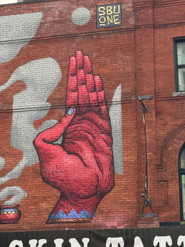 SbuOne Symbolic Mural Lowertown Ottawa. Red-faced figure with a third eye and blue bird on shoulder. Animistic Street Art.