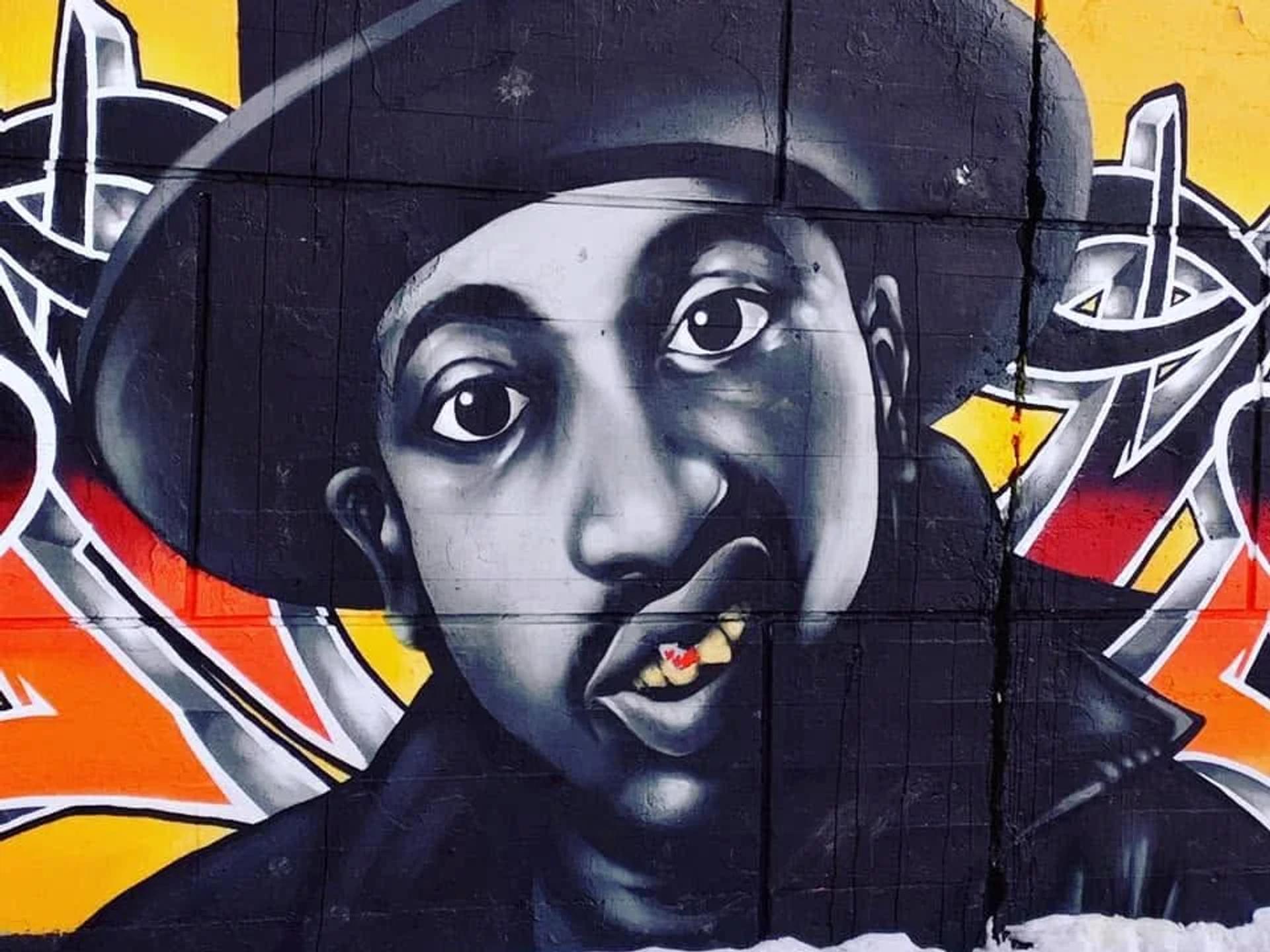Mural portrait of a grayscale man in a fedora, with a red maple leaf on a gold tooth, against colorful graffiti, Centretown, Ottawa.