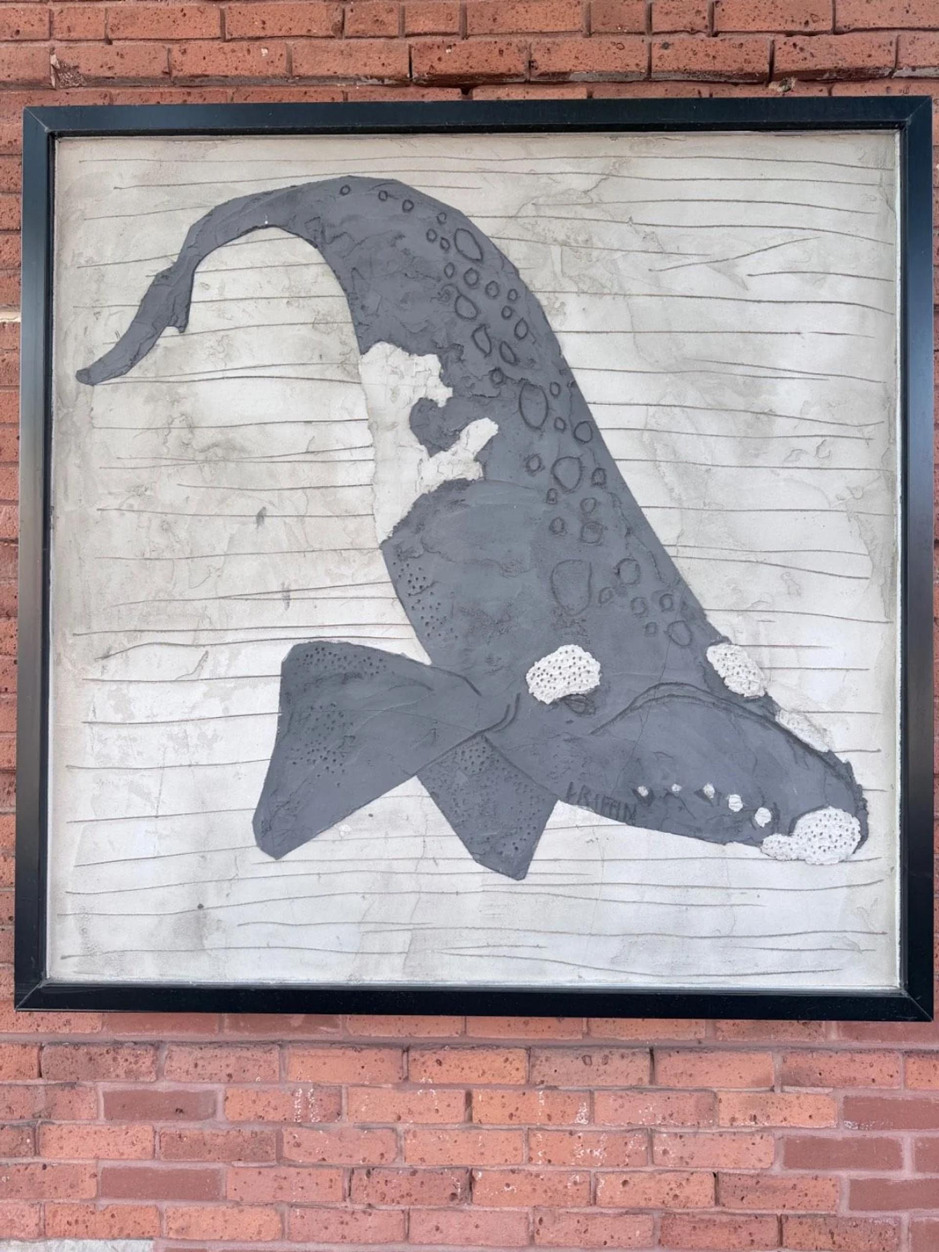 Framed dark grey whale relief mural by Griffin with white textures on light grey, mounted on a brick wall, Centretown West, Ottawa.