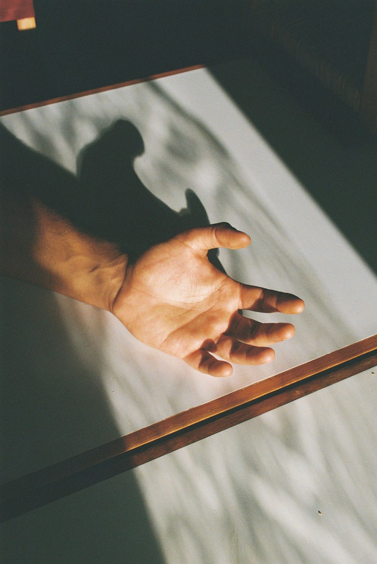 Mano abierta sobre una mesa con sombras