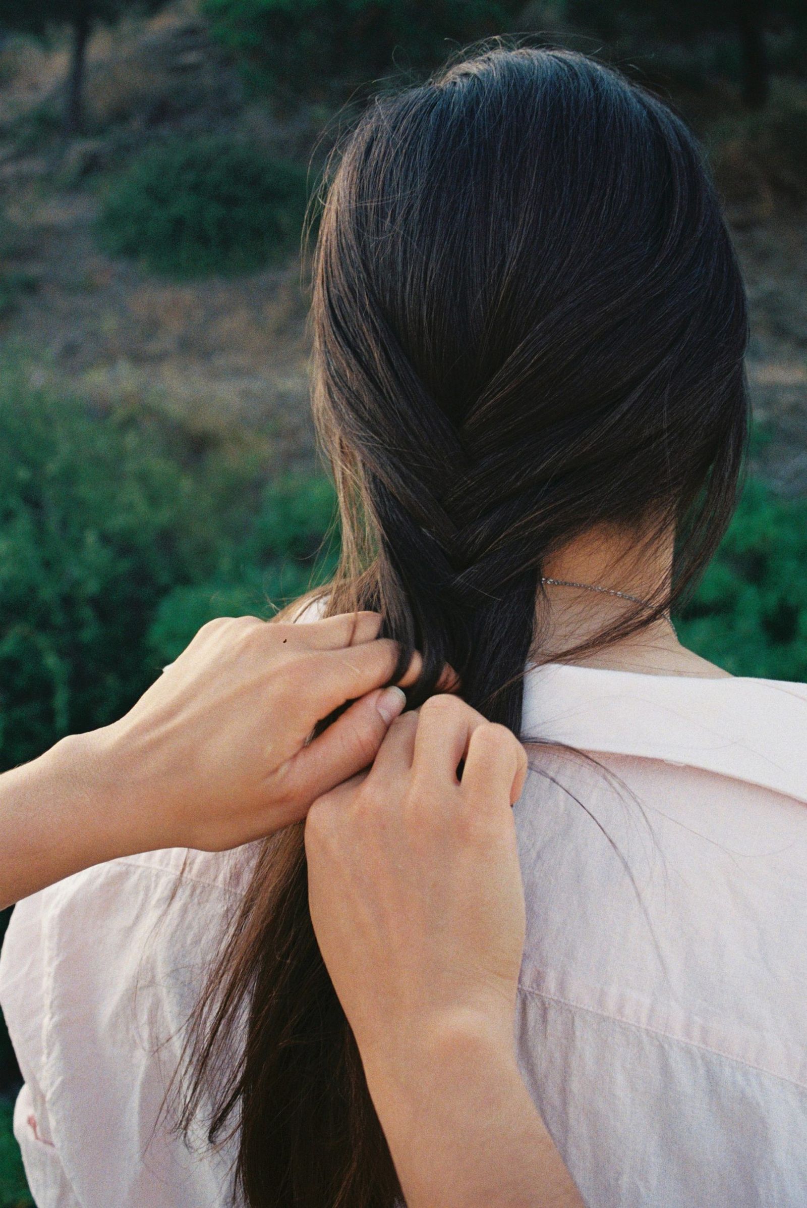 Manos trenzando el pelo de una mujer de espaldas