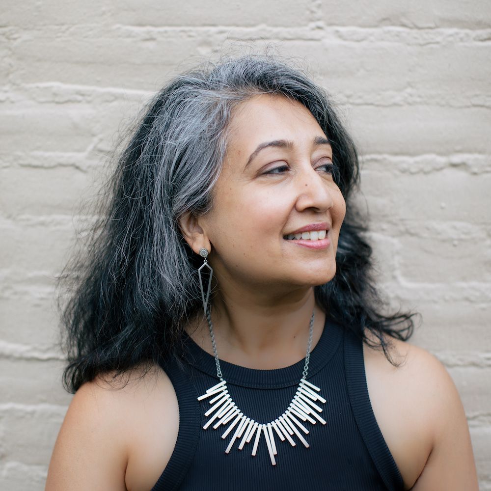 Hasanthika Sirisena in a black shirt against a white brick wall