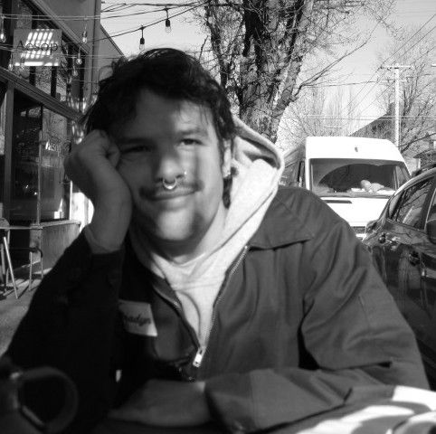 kurt holding 2 hot dogs with mustard and a bbq rib wearing a heavy metal t-shirt and a green bench brewing hat