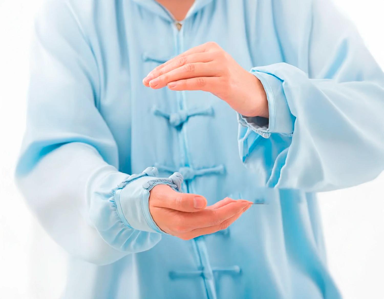 Mani in una postura di Qi Gong davanti a una giacca tradizionale azzurra.