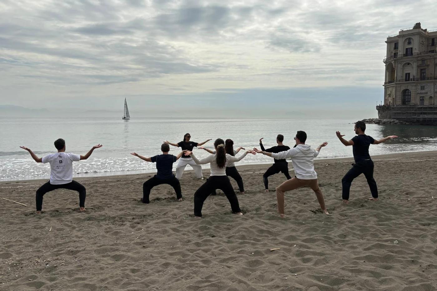 Un gruppo pratica Dao Yin sulla spiaggia davanti al golfo di Napoli.