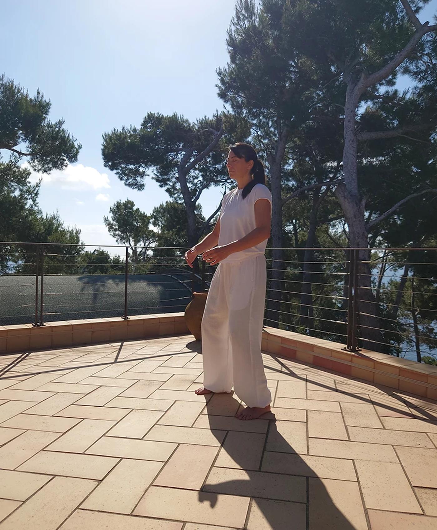 Carolina Inda pratica Dao Yin su una terrazza tra i pini.