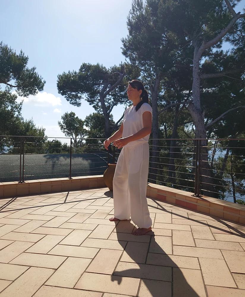 Carolina Inda pratica Dao Yin su una terrazza tra i pini.