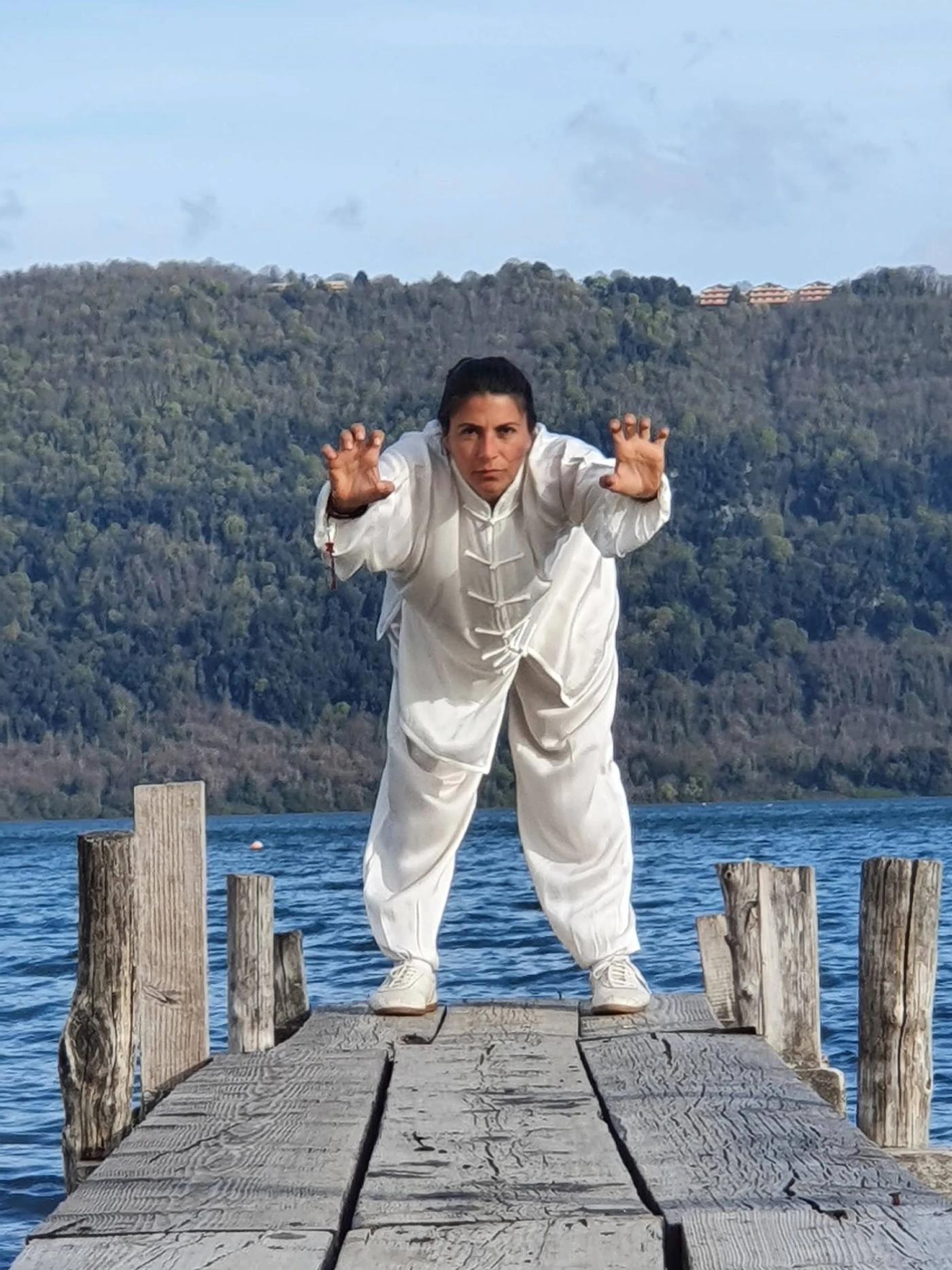 Carolina Inda in una postura di Qi Gong a braccia tese sul pontile.