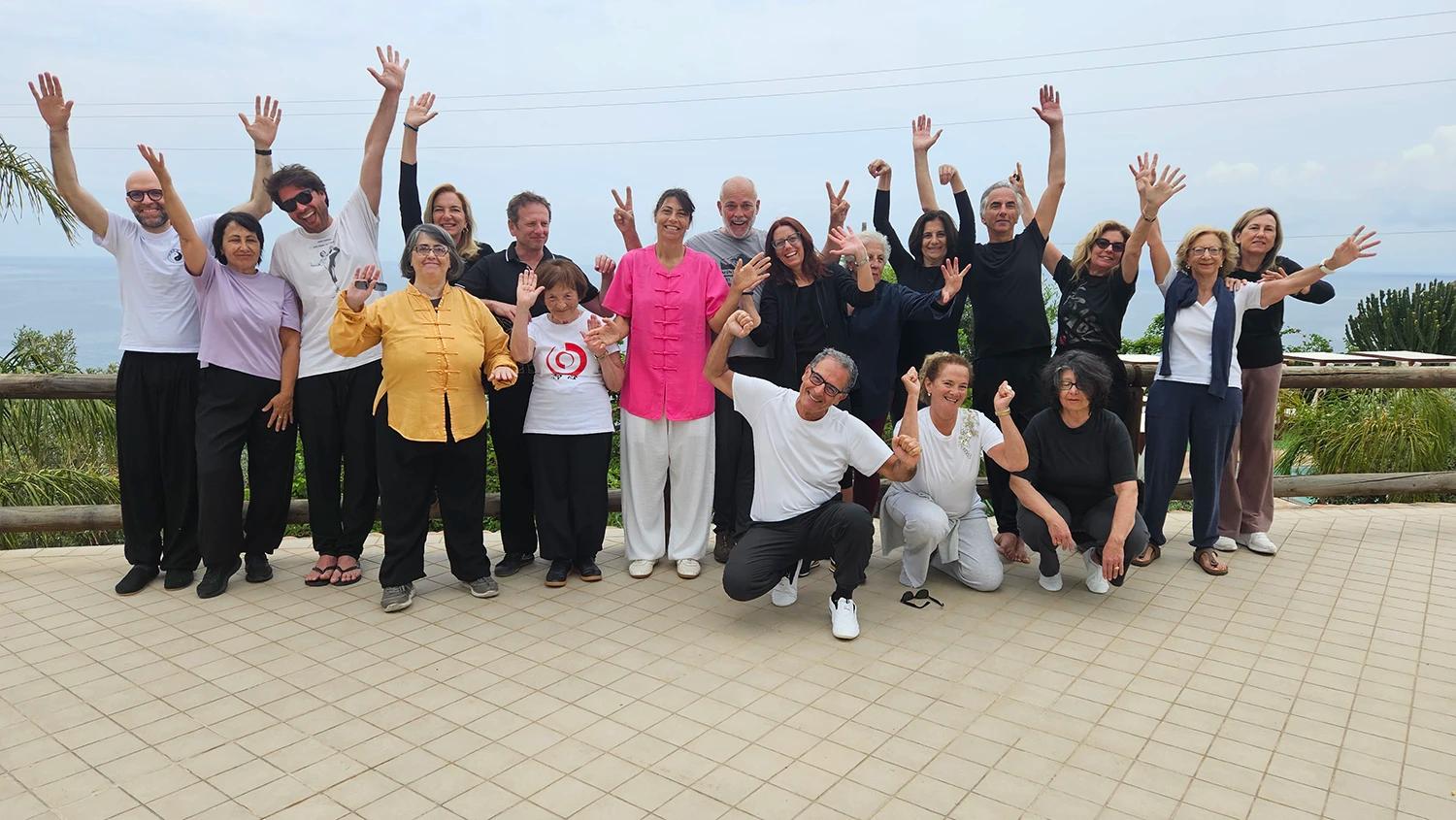Il gruppo della scuola Chu Xin festeggia a braccia alzate su una terrazza affacciata sul mare.
