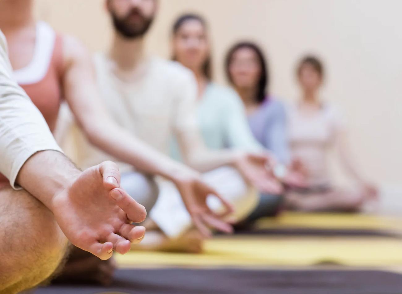 Un gruppo medita a gambe incrociate in una sala.
