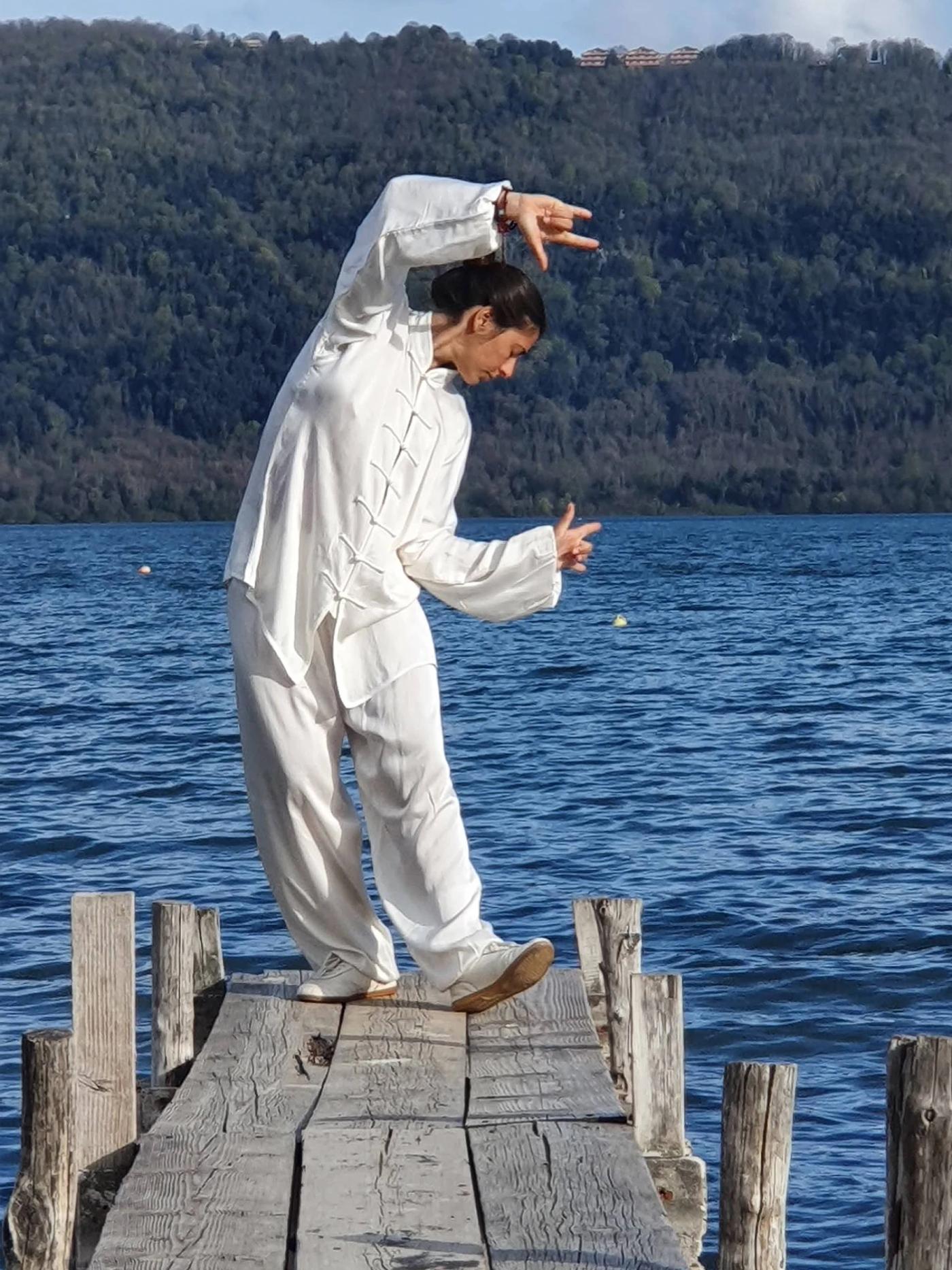Carolina Inda in una posizione di Qi Gong su un pontile sul lago.