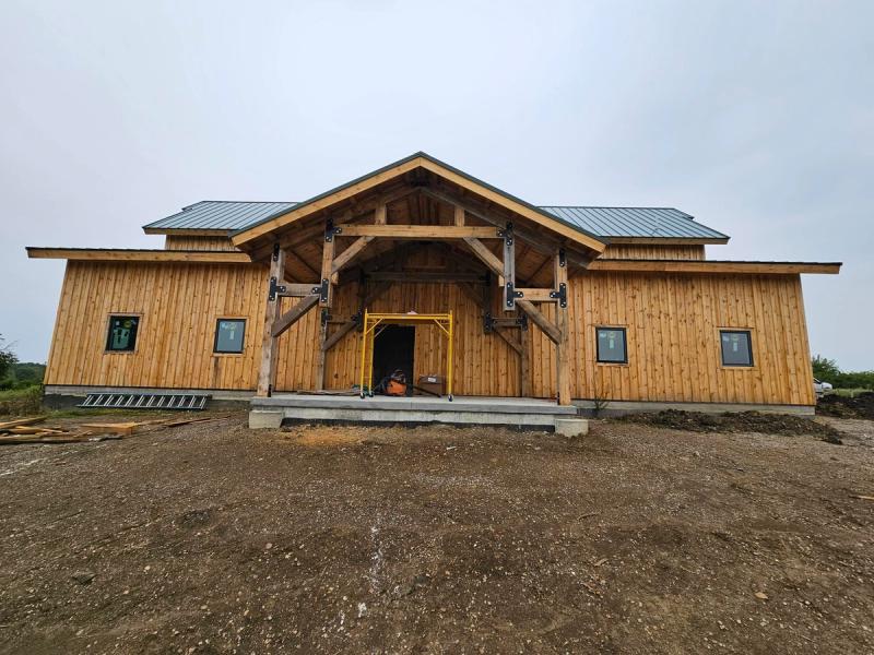 The completed Paola, Kansas barndominium built by All Under One Roof, with its heavy timber entry truss & covered wings to either side