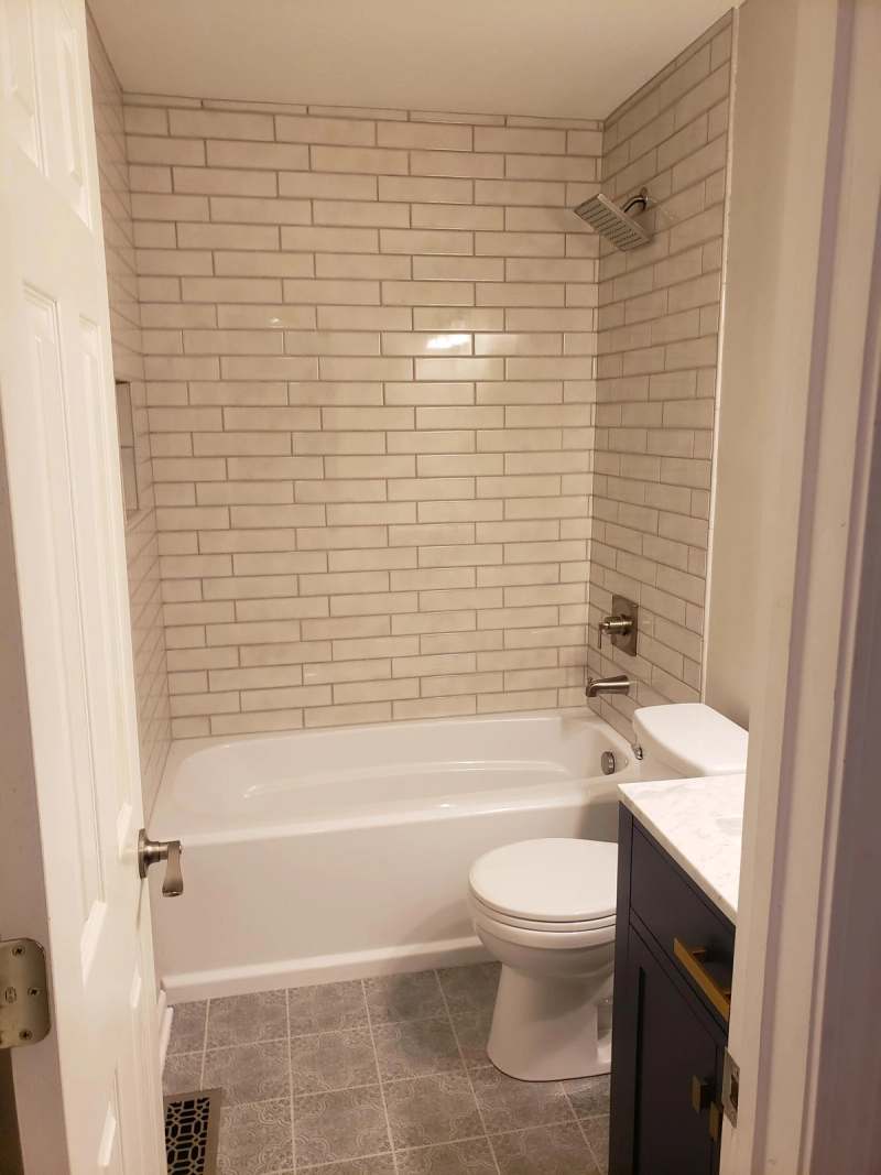The hall bath with a tub surrounded by white subway tile to the ceiling