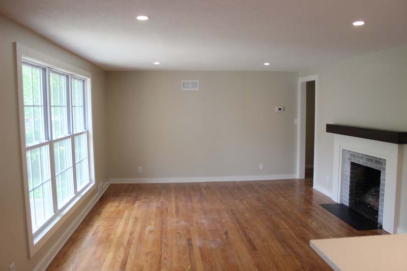 The living room with refinished oak floors, a wide double hung window & the refaced fireplace