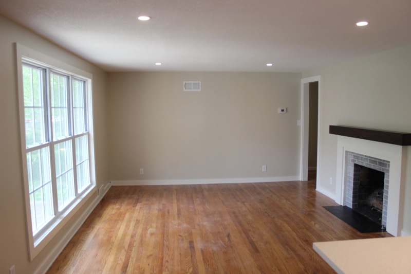 The living room with refinished oak floors, a wide double hung window & the refaced fireplace