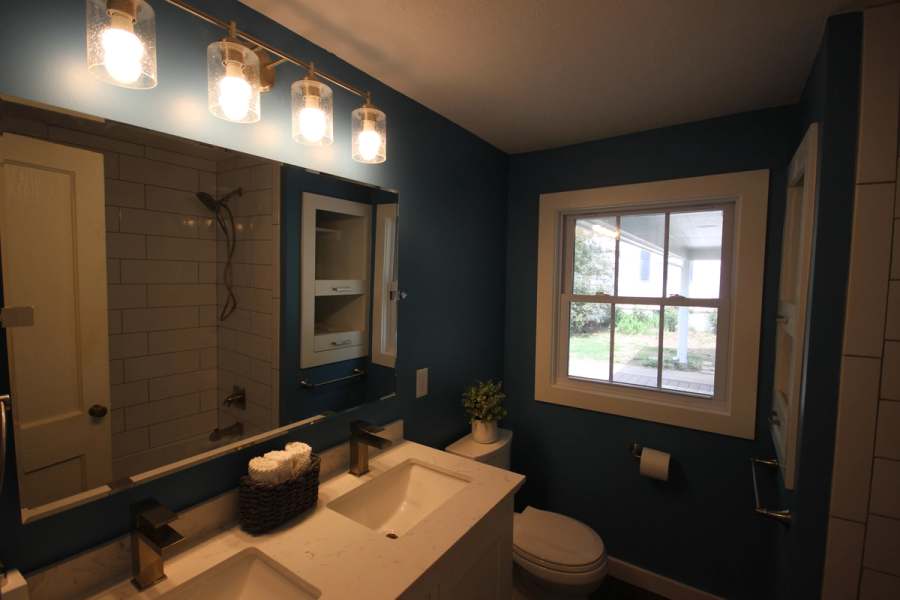 The same hall bath after: a quartz vanity, glass shade lights, blue walls & new window trim
