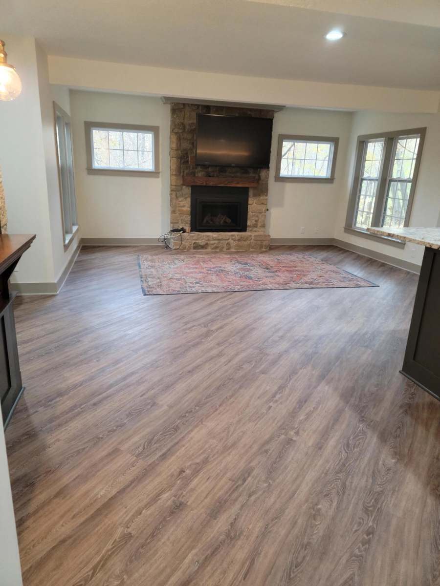 The same room after: vinyl plank floors, light walls & the stone fireplace kept as the focal point