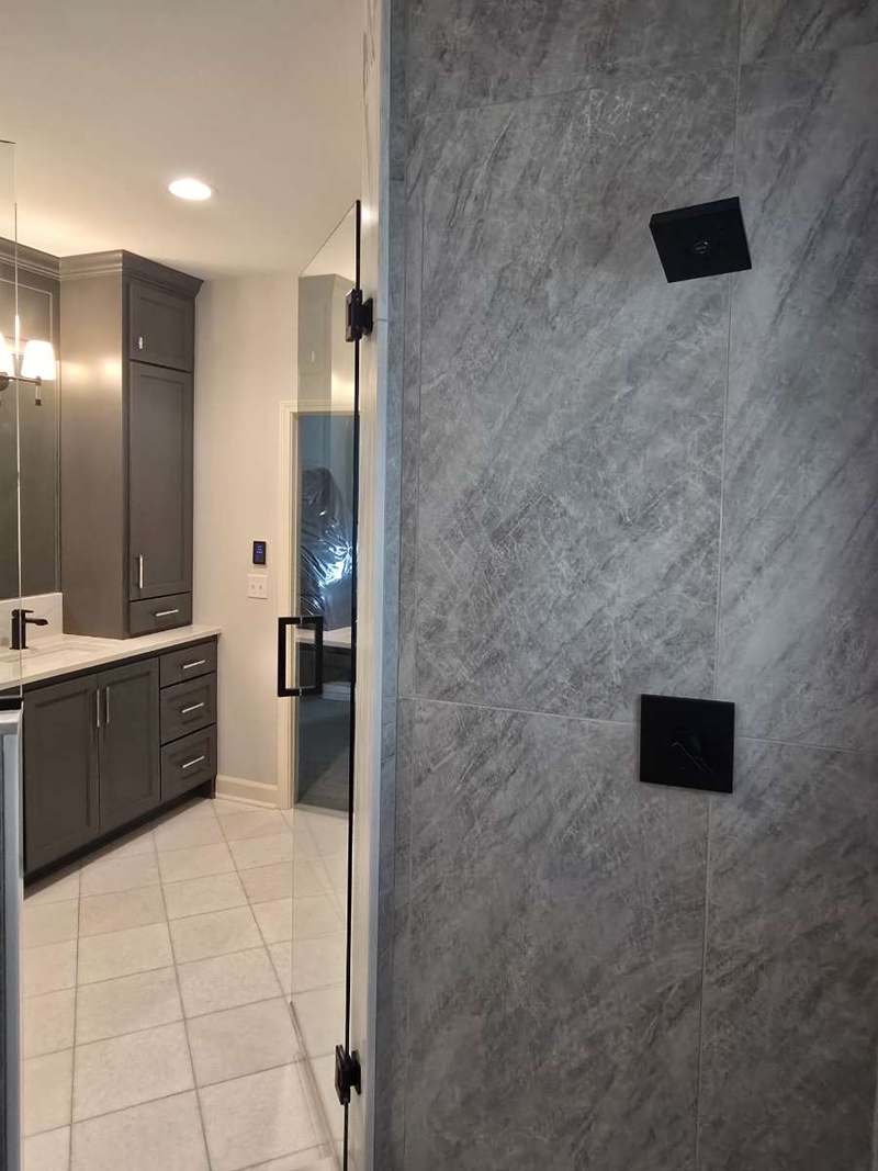 Frameless glass shower enclosure with the vanity & linen tower beyond