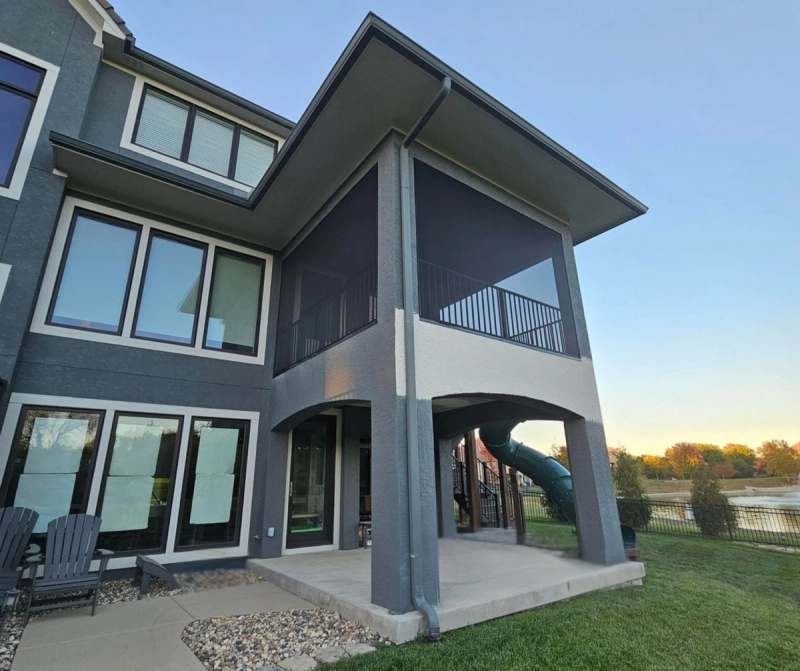 The rear of the house at dusk, showing how the porch, deck & lower patio stack over one another