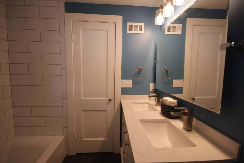 The hall bath double vanity with a quartz top & two sinks across from the tiled tub