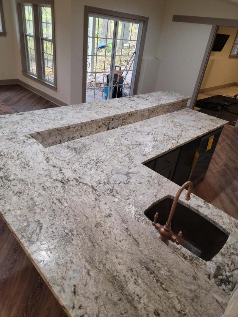 Granite bar top with a dark undermount sink & a copper bar faucet