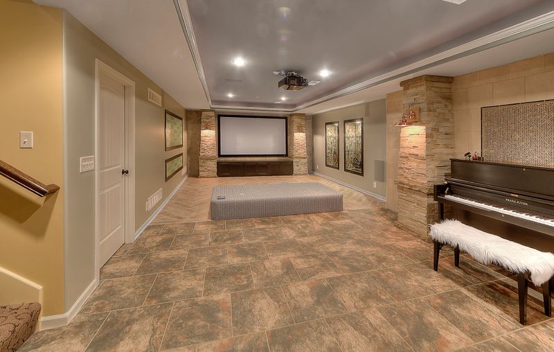 Finished basement with a projector screen, tile flooring, and a piano along the wall