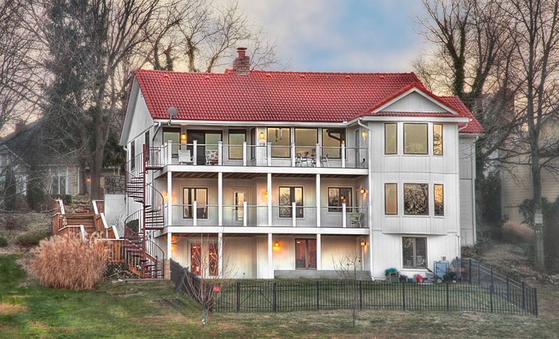Three story home exterior with a red metal roof and rebuilt covered porches