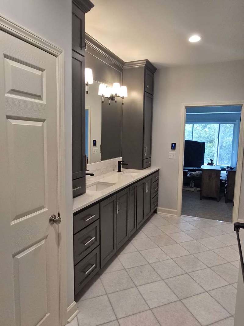 The finished vanity run seen from the bathroom doorway, showing the full cabinetry wall & tiled floor