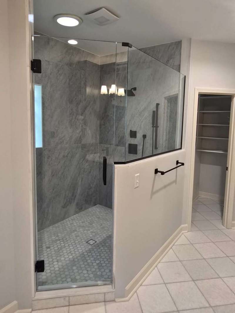 Walk in shower with frameless glass, grey marble look porcelain tile & a penny round mosaic floor