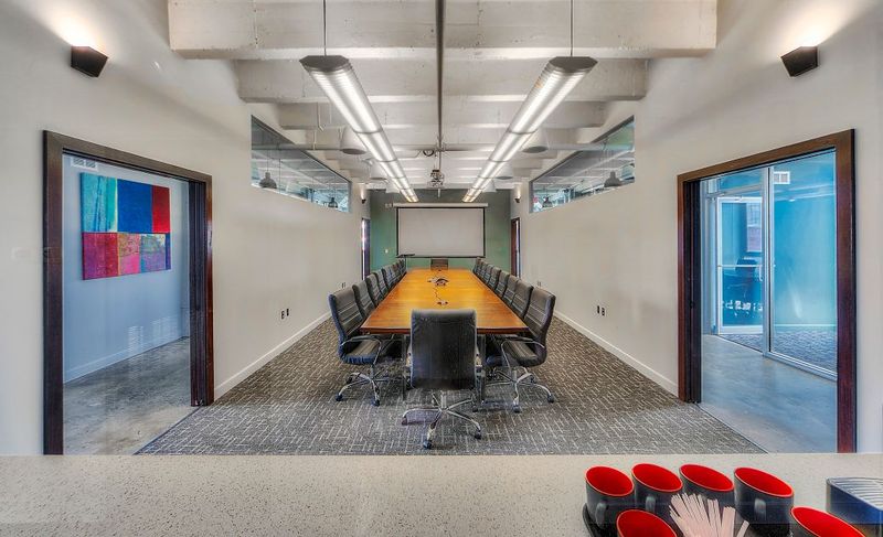 Commercial conference room with glass side offices and a projector screen