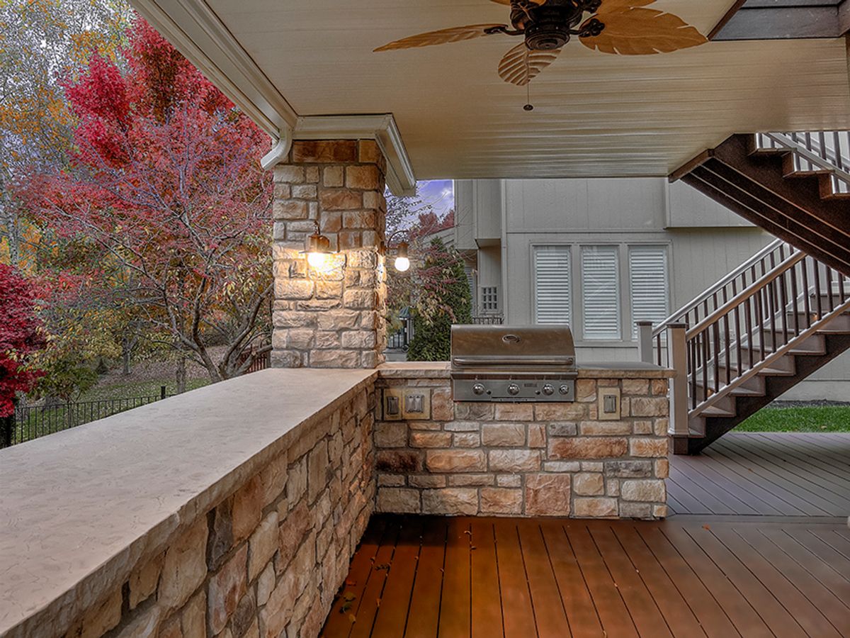 Outdoor kitchen by All Under One Roof with a built-in stainless grill set into a stone masonry island, Kansas City