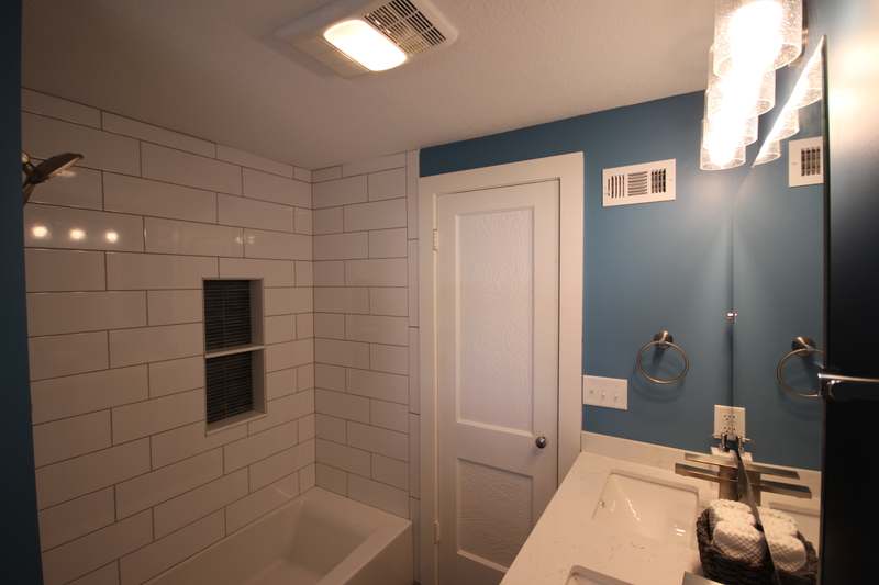Tub surround in white subway tile with a recessed niche set in dark tile
