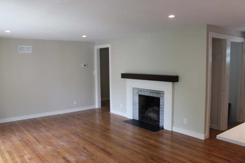 The refaced fireplace with a white surround, gray tile & a dark timber mantel