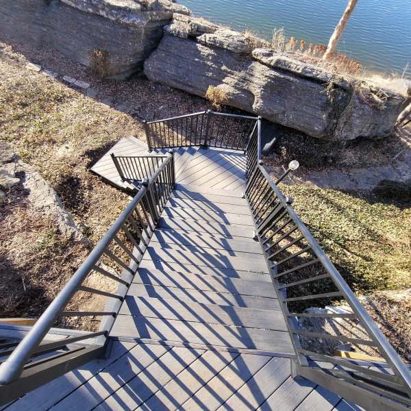 The composite stairway with black aluminum rails running down a limestone bluff to the lake landing in Lee's Summit, Missouri